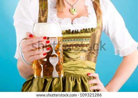 Young woman in traditional Bavarian clothes - dirndl or tracht with a beer stein and beer