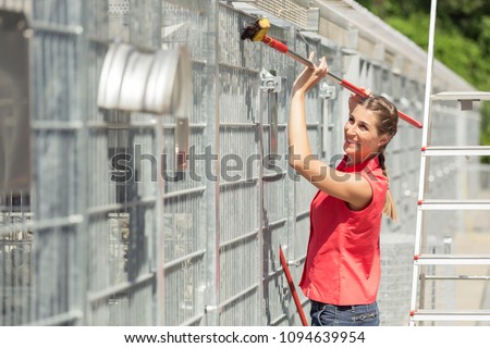 Zookeeper woman working on cleaning cage in animal shelter with sweep