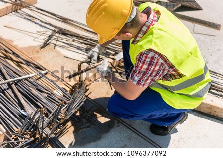 Side view of a reliable worker checking the quality of the steel bars, before using them for the reinforcement of the structure of a building under construction