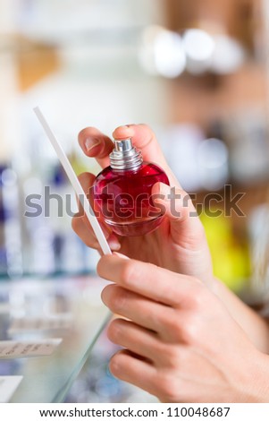 Young woman (only hands to be seen) buying perfume in a shop or store, testing the fragrance with a paper tester