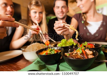 Young people eating in a Thai restaurant; they eating with chopsticks