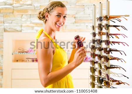 Young woman at optician with glasses, she might be customer or salesperson and is wearing sunglasses