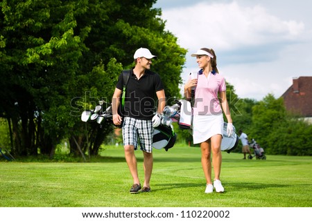 Young sportive couple playing golf on a golf course, they walking to the next hole