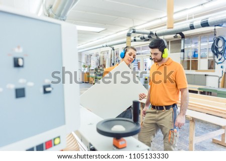 Carpenter in furniture factory inspecting piece in QA being satisfied
