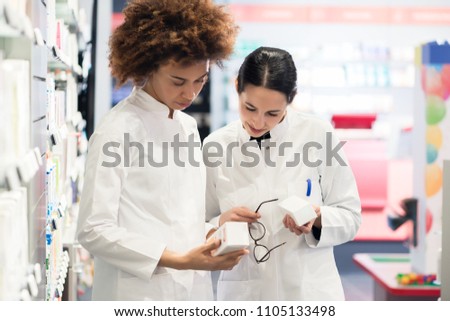 Side view of two dedicated female pharmacists looking for the best medicine in the stock while working together in a contemporary pharmacy