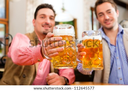Two friends in Bavarian pub in traditional clothes sitting on their regular table in a pub