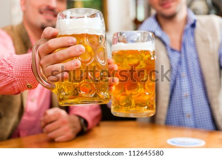 Two friends in Bavarian pub in traditional clothes sitting on their regular table in a pub