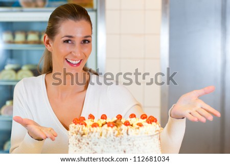 Female baker or pastry chef with black forest cake in bakery