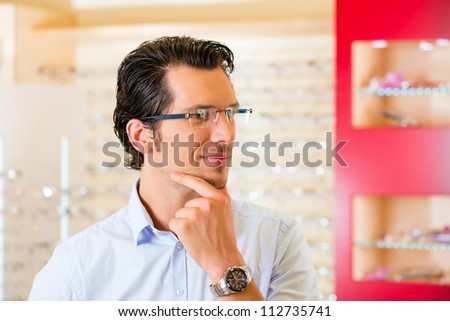 Young man at optician with glasses, he might be customer or salesperson