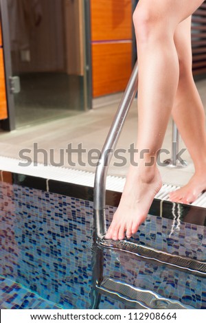 Young woman walking into water basin in a wellness hotel for cooling down after sauna, only feet to be seen