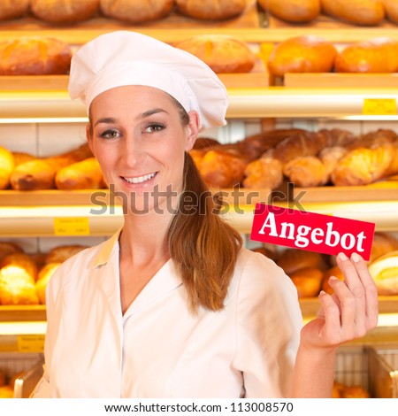 Female baker or saleswoman in her bakery selling fresh bread, pastries and bakery products, she hold a sign in her hand saying \