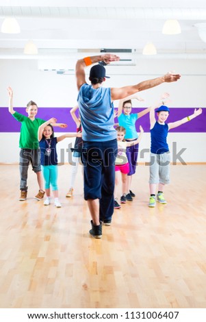 Dance teacher giving children fitness class in gym