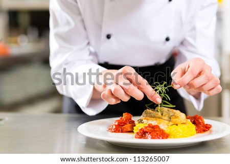 Female Chef in hotel or restaurant kitchen cooking only hands she is finishing a dish on plate Female Chef in hotel or restaurant kitchen cooking only hands she is finishing a dish on plate