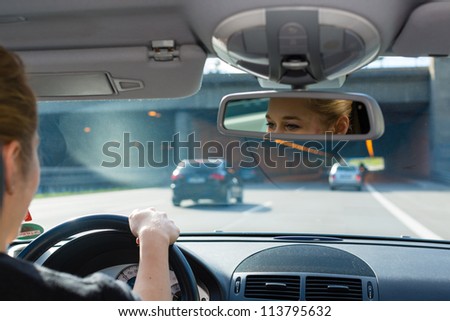 Young woman driving by car on the autobahn, view from inside the auto