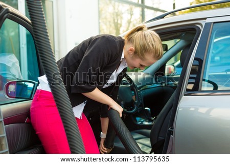 Young woman cleaning her car with a vacuum cleaner