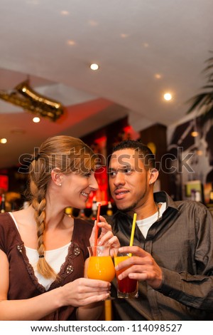 Young happy couple drinking cocktails in bar or restaurant, presumably it is a first date