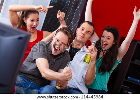 Two couples watching sports in the telly, they all are really excited, drink beer and cheer their team