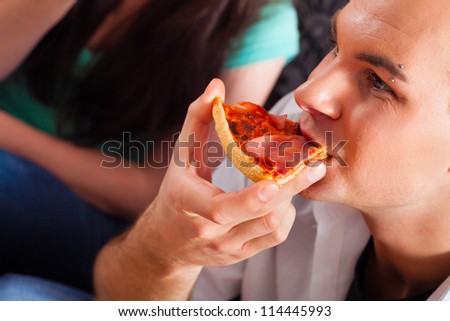 Good friends sitting together having a good time and some tasty pizza for lunch, focus on one man
