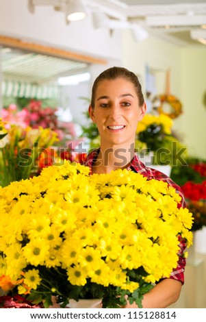 Female florist in flower shop or nursery presenting flowers