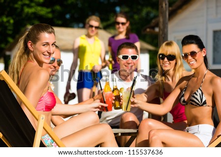 People at beach drinking having a party, friends clinking glasses with cocktails and beer having fun