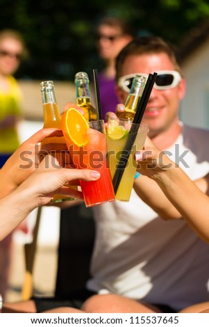 People at beach drinking having a party, friends clinking glasses with cocktails and beer having fun