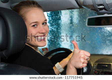 Young woman drives car in wash station cleaning the auto