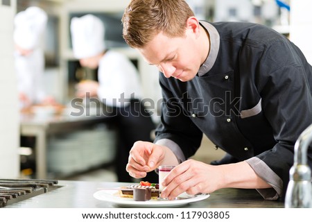 Cook, The Pastry Chef, In Hotel Or Restaurant Kitchen Cooking, He Is Finishing A Sweet Dessert