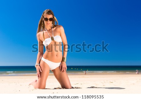 Attractive Woman in white bikini sitting in the sun on beach, a lot of   blue sky
