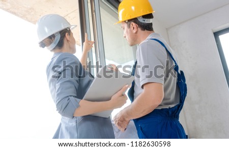 Architect woman and construction worker checking windows on site