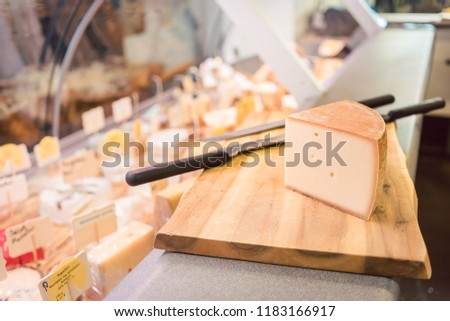 Cheese on a board at counter in delicatessen shop or deli