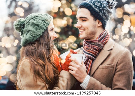 Woman and man drinking mulled wine on Christmas Market in front of tree