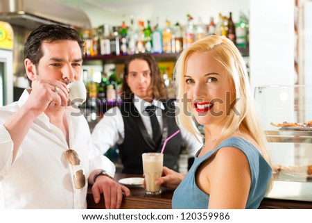 Attractive couple in cafe or coffeeshop, in the background the barista to be seen