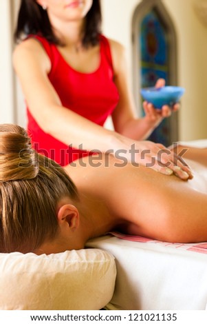 Woman receiving a massage in wellness spa by a masseuse