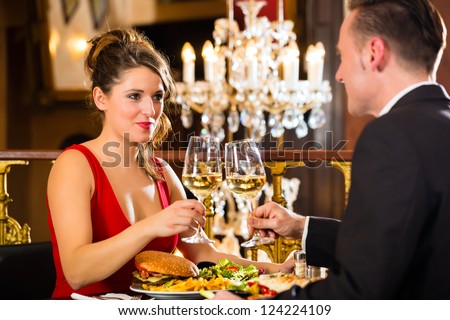 happy couple have a romantic date in a fine dining restaurant, a large chandelier is in Background