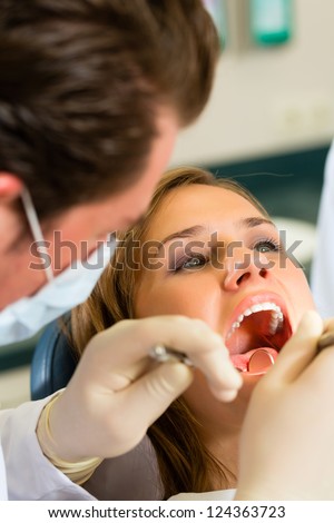 Female patient with dentist in a dental treatment wearing masks and gloves Female patient with dentist in a dental treatment wearing masks and gloves