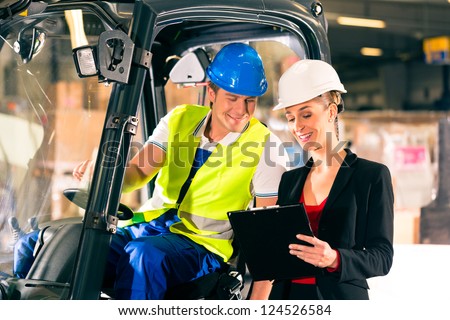 Forklift driver and female super visor with clipboard at warehouse of freight forwarding company