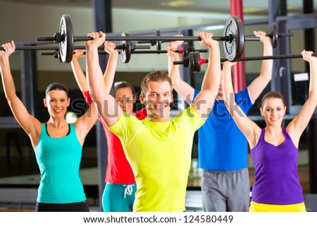 group of young sport people training with barbell at a gym for better fitness