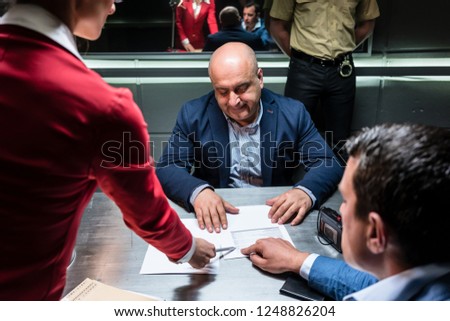 Middle-aged defendant or witness, counseled by the lawyer to sign an official statement in front of the prosecutor during a criminal investigation in the police station
