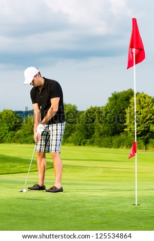 Young golf player on course putting the ball to the hole
