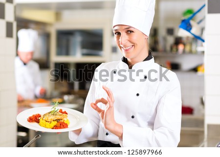Female Chef in hotel or restaurant kitchen cooking, she is presenting a dish on plate