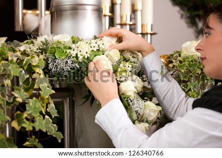 death and dolor  - mortician on funeral with urn preparing the flowers