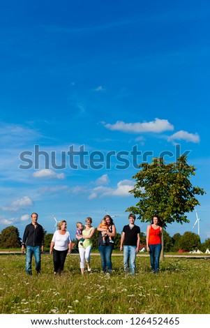 Family and multi-generation - mother, father, children and grandmother having fun on meadow in summer
