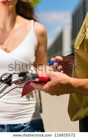 Police - young woman on bicycle with police officer in traffic control