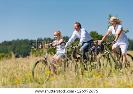 Family with baby and and daughter having a weekend excursion on their bikes on a summer day in beautiful landscape