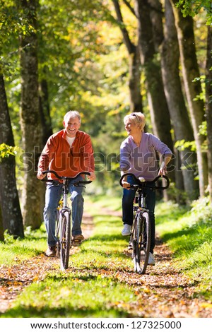 Senior Man and woman exercising with bicycles outdoors, they are a couple