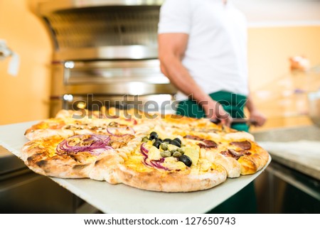 Man pushing the finished pizza from the oven with the pizza shovel