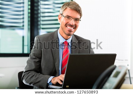 Business - Boss in his office checking mails on laptop computer