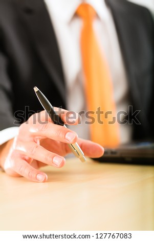 Business - Boss in his office checking mails, in his hand he holds a pen, closeup