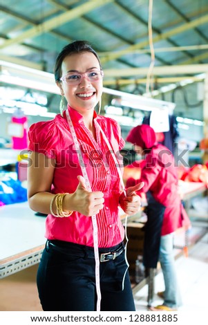 Female asian dressmaker or designer standing proudly in a textile factory, it is her workplace