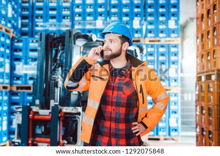 Worker in logistics warehouse on the phone receiving instructions